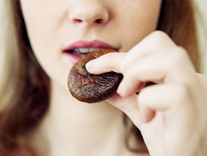 Femme qui mange une figue séchée naturelle