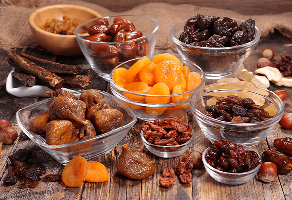 Bols de fruits séchés sur une table : abricots secs, raisins secs, figues séchées, dattes et pruneaux